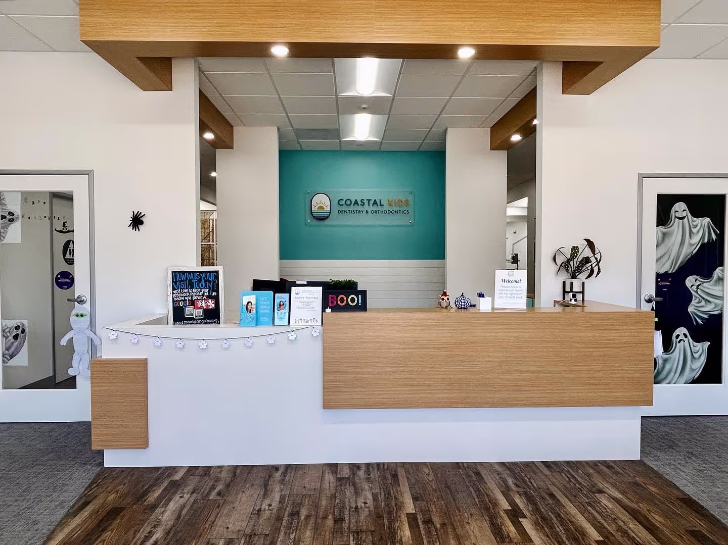 Reception desk of Coastal Kids Dentistry & Orthodontics decorated with Halloween ghost and spider decorations.