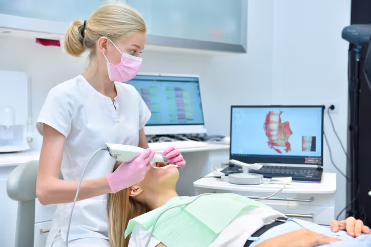 Dental professional using an intraoral scanner on a patient's upper teeth in a dental office.