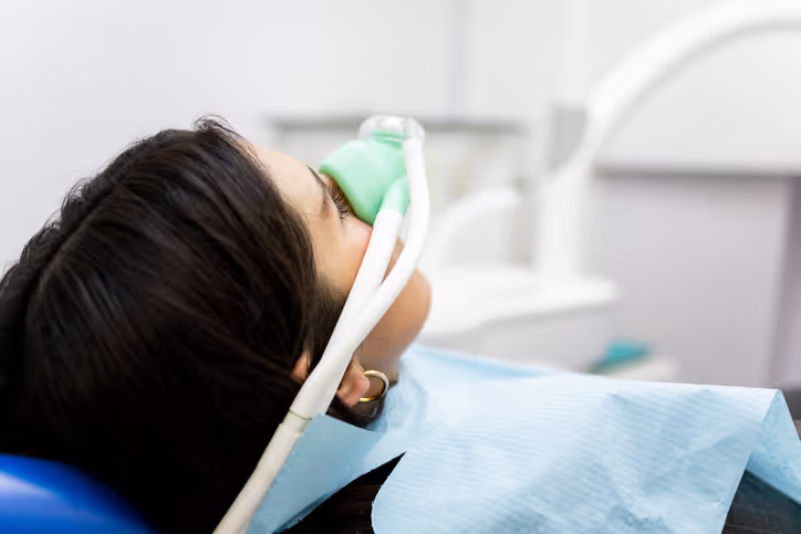 Patient reclining in a dental chair receiving nitrous oxide sedation through a nose mask.