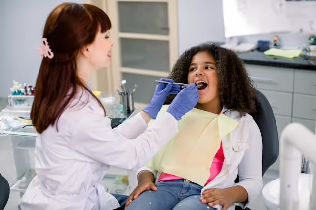 A pediatric dental team member caring for a smiling child in the dental chair.